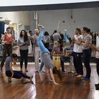 Photo of dancers cartwheelling and crouching, with people stood around clapping