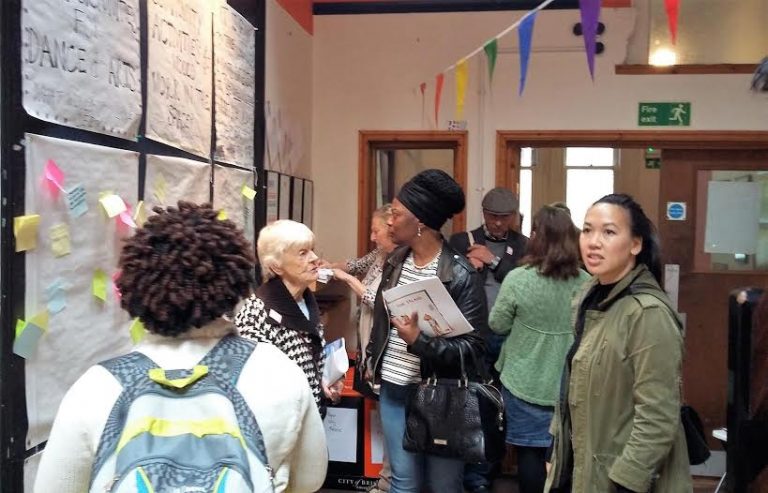 Photo of people looking at wall exhibition with bunting overhead