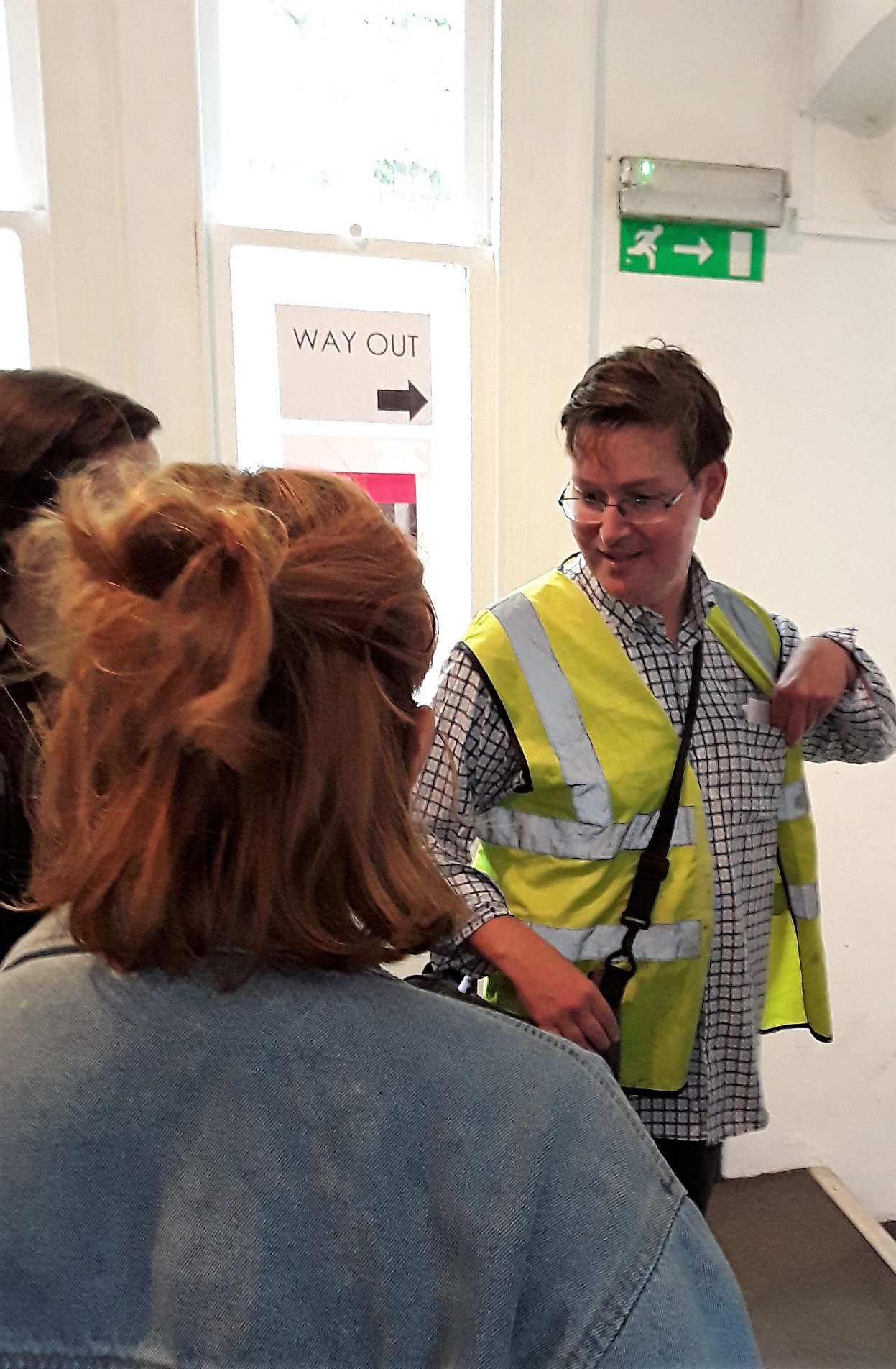 Man in high
visibility jacket takes people on a tour out of the building