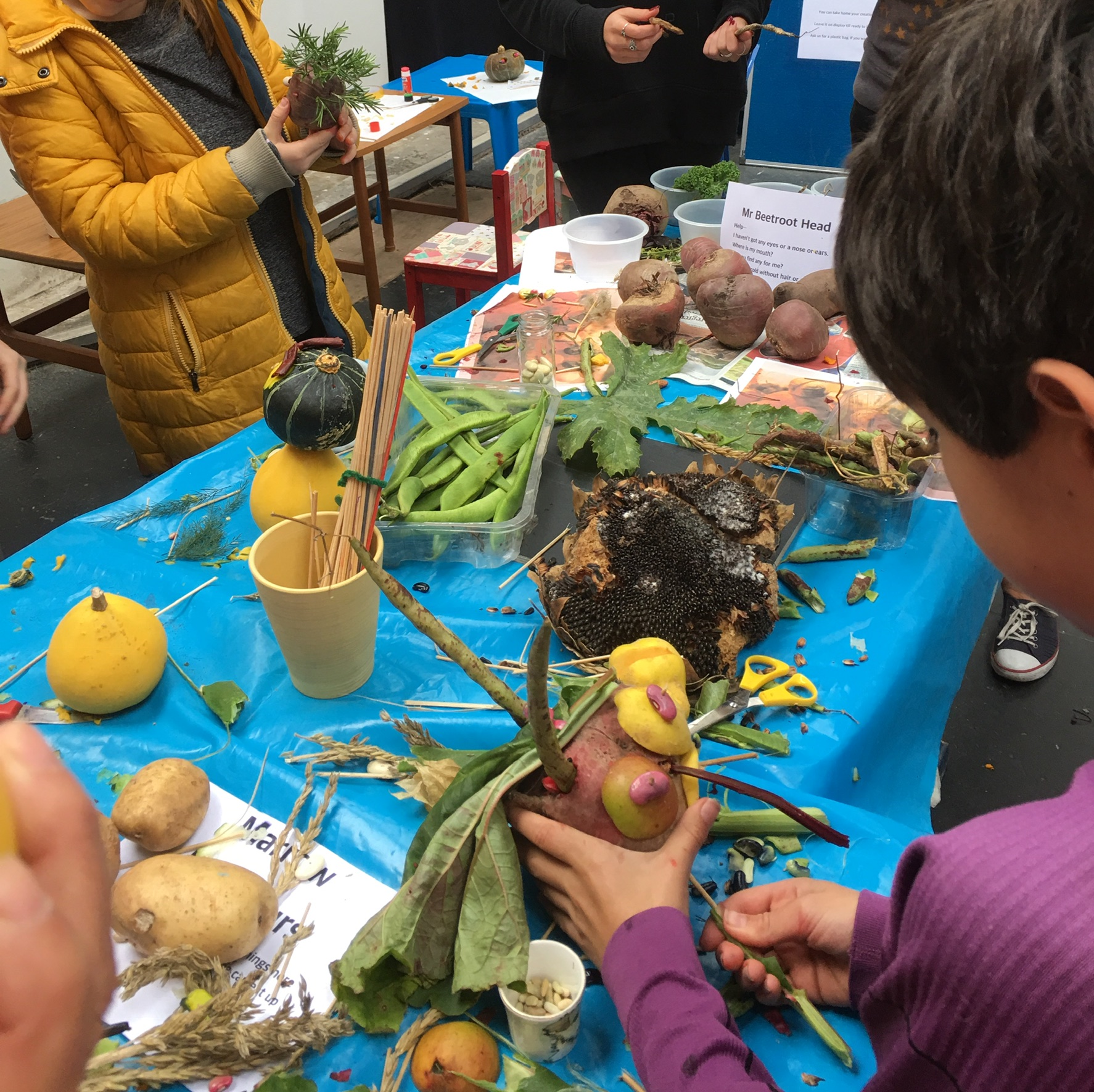 People crafting potato heads, with vegetables and a sunflower