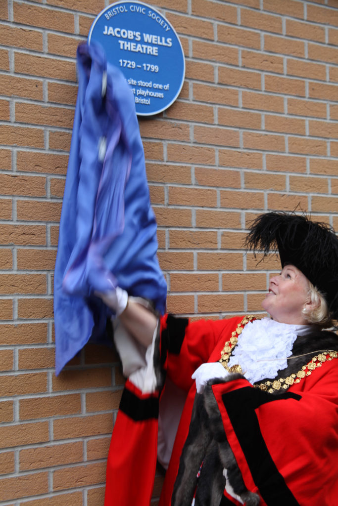 Photo of blue
plaque being unveiled by a councillor in elaborate red robes and golden chain