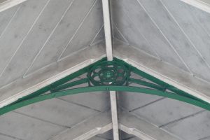 Photo of metal roof truss with decorative flower pattern, painted green