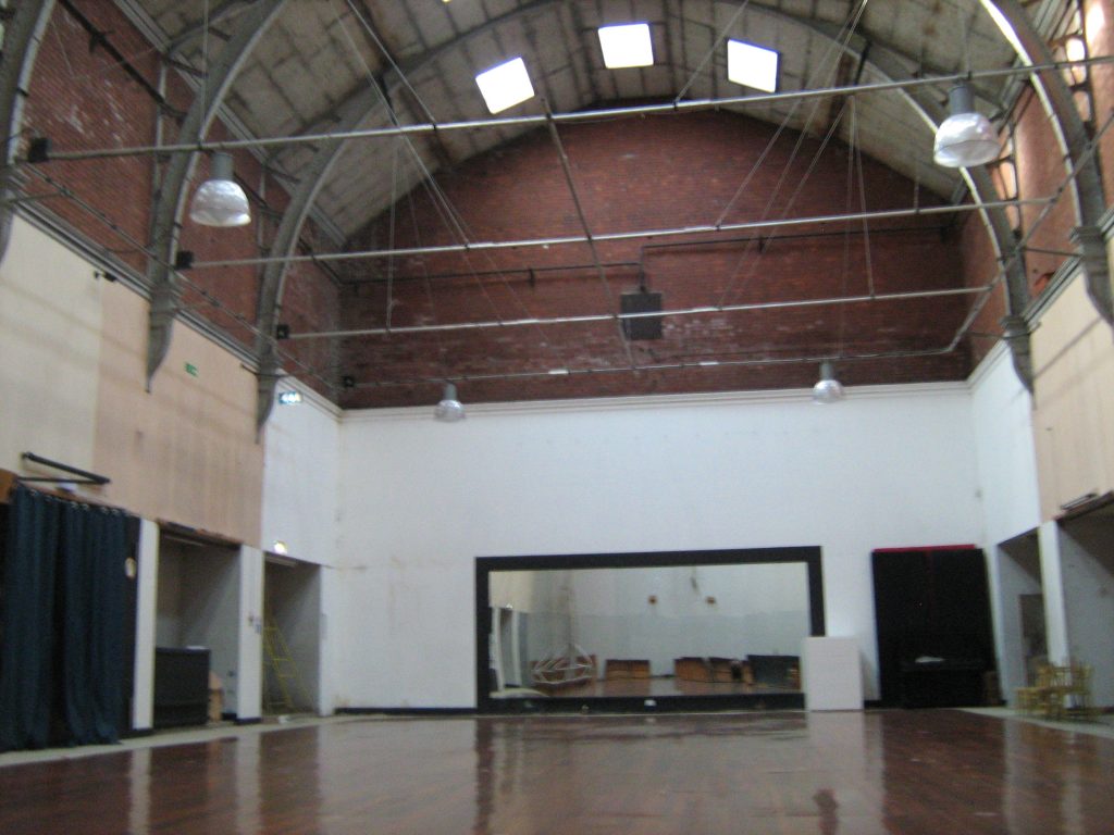 Photo of the swimming pool hall, with shiny floor over the pool and largemirror on the back wall